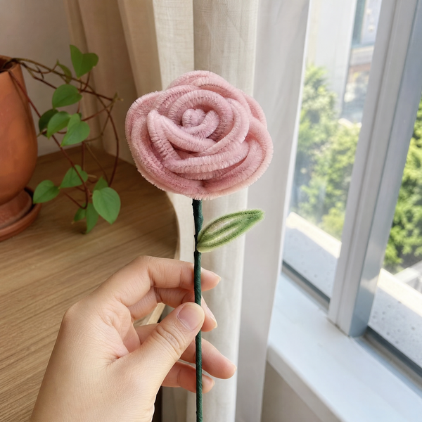 Mano sosteniendo una rosa de limpiapipas